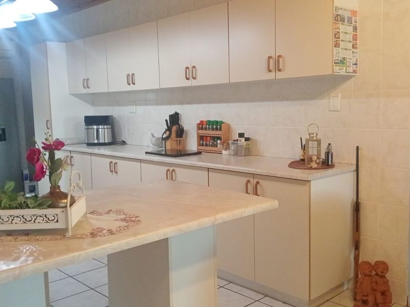 A functional kitchen featuring ample built-in cabinetry, laminate countertops, tiled backsplash, and tiled flooring, providing a practical workspace for daily cooking.