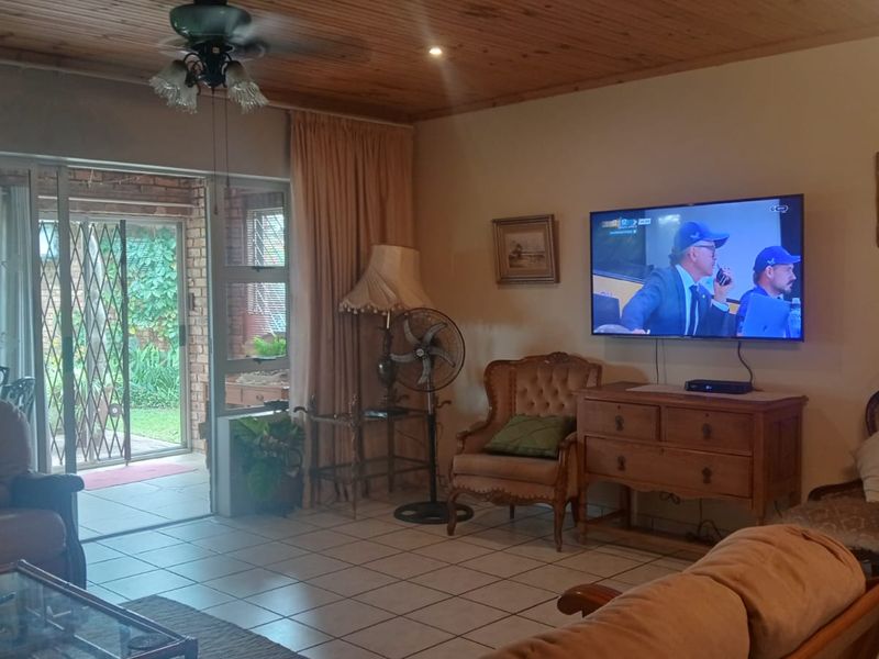 A comfortable living room featuring a timber ceiling, tiled flooring, and a sliding glass door providing direct access to the outdoor patio area.