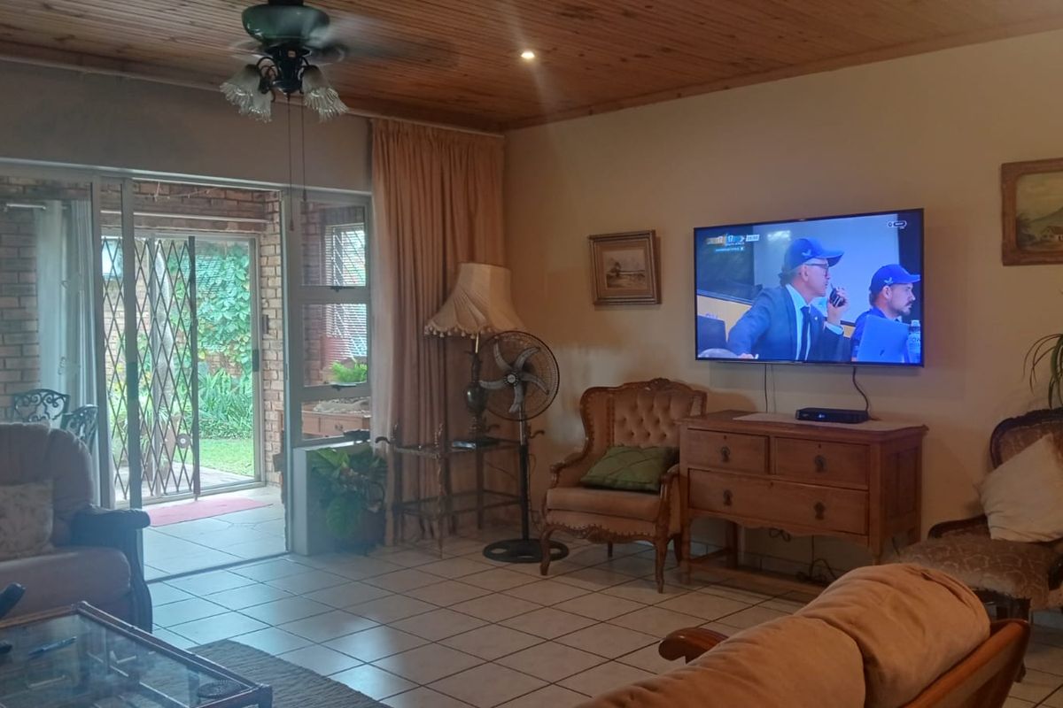 A comfortable living room featuring a timber ceiling, tiled flooring, and a sliding glass door providing direct access to the outdoor patio area.