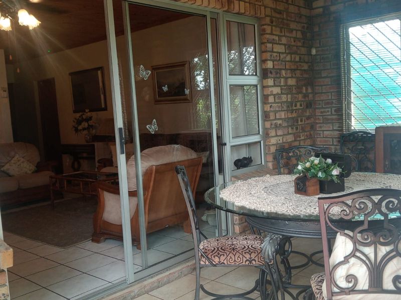 A covered patio area featuring exposed brick walls, tiled flooring, and sliding glass doors that provide access to the interior living space.