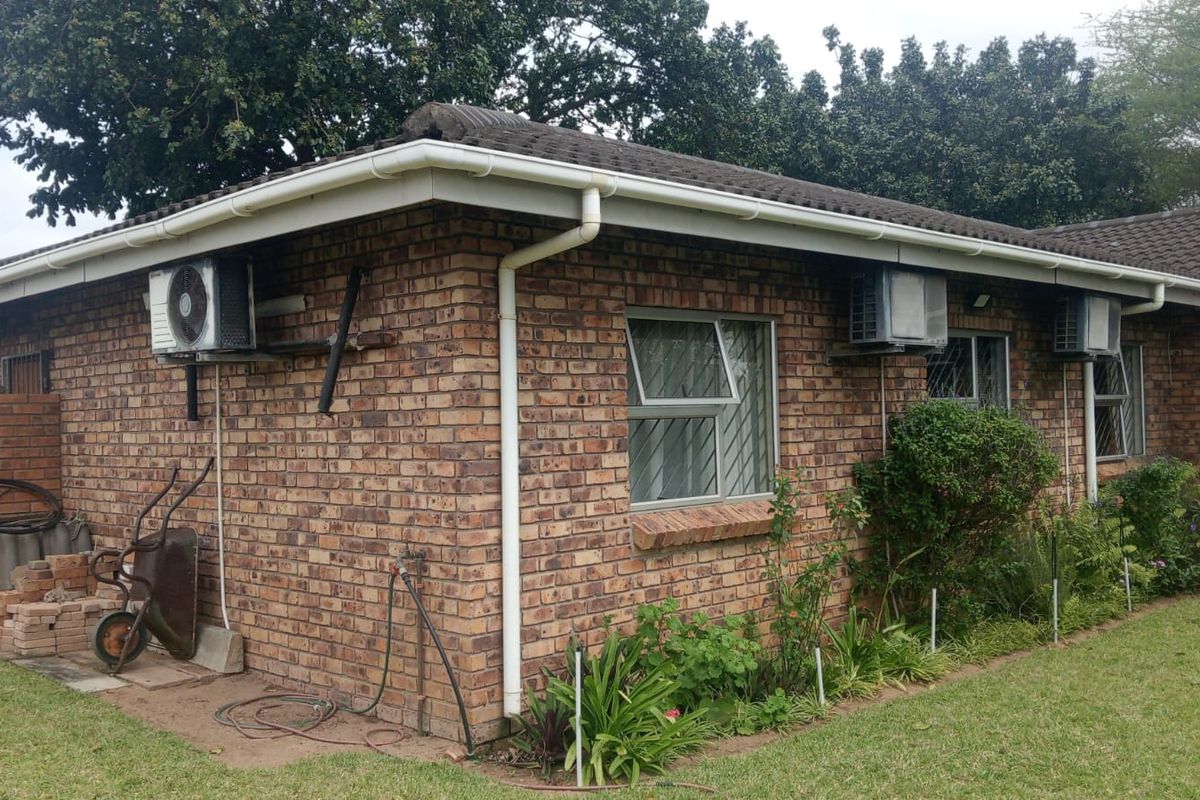 Rear view of a face brick house featuring tiled roofing, guttering, and multiple wall-mounted air conditioning units.