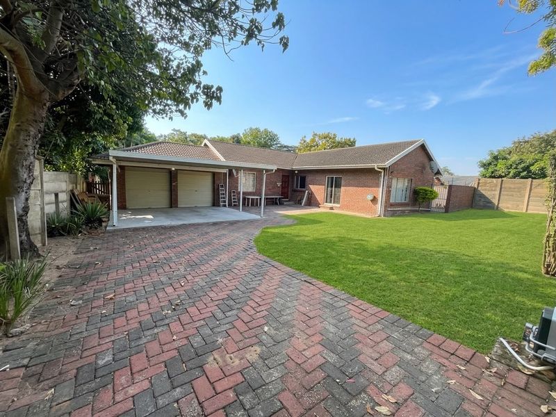 Front view of a brick house featuring a double garage, paved driveway, and a well-maintained lawn.