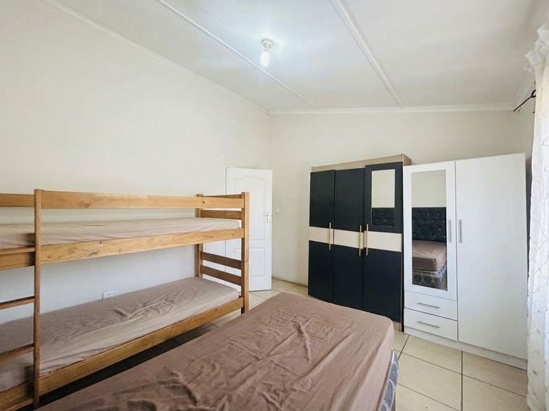 A functional bedroom featuring tiled flooring and a built-in cupboard, providing practical storage space.
