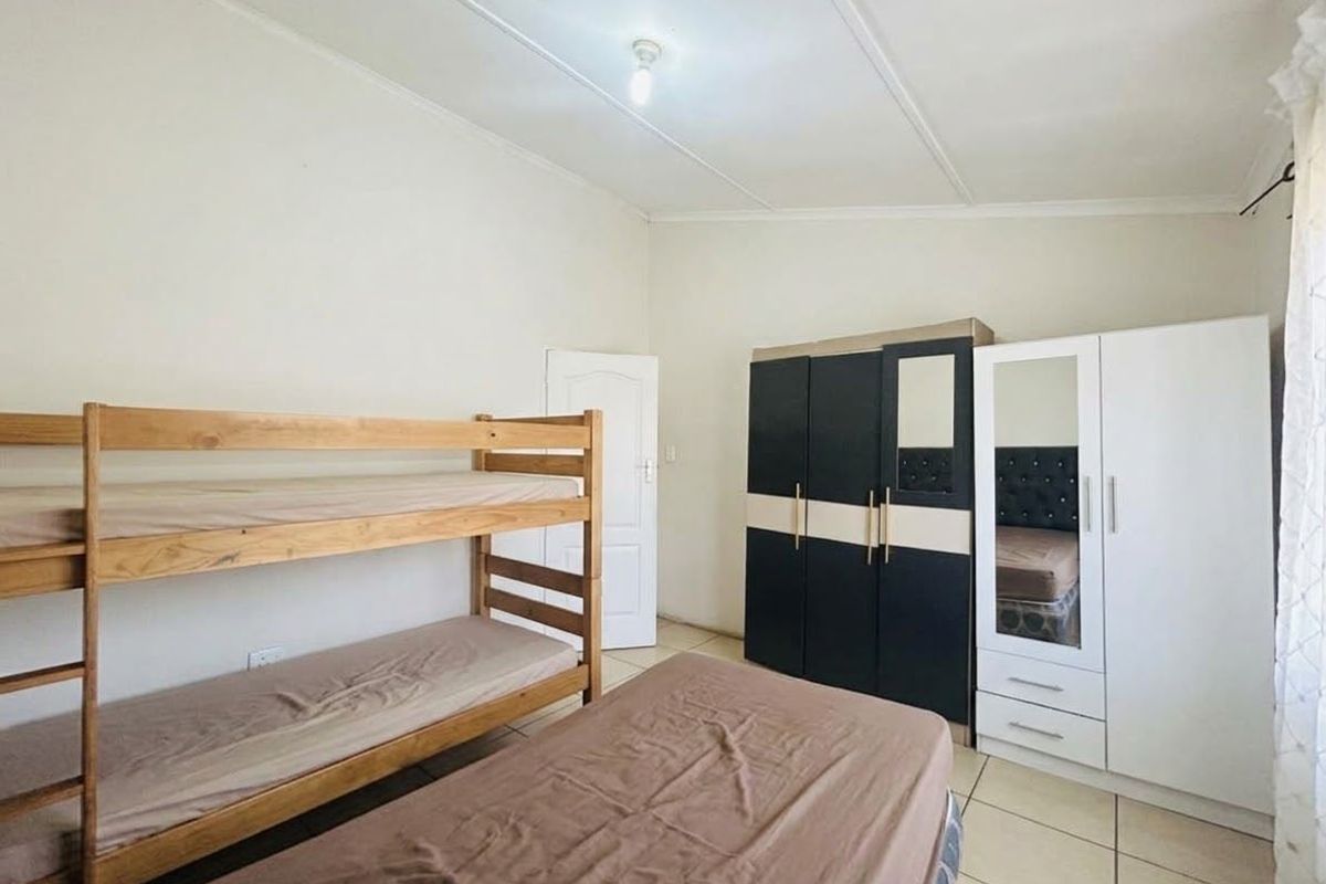 A functional bedroom featuring tiled flooring and a built-in cupboard, providing practical storage space.