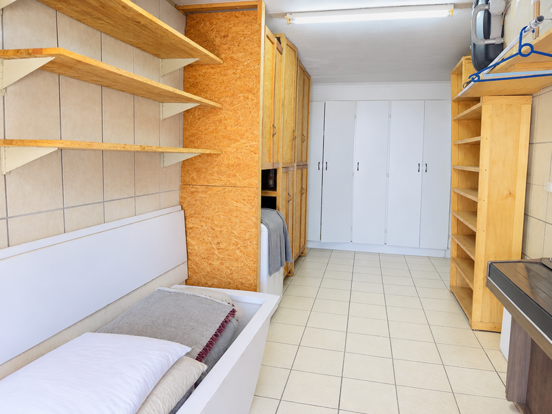 A functional laundry room featuring extensive built-in cabinetry, open shelving, and tiled flooring, providing ample storage and utility space.
