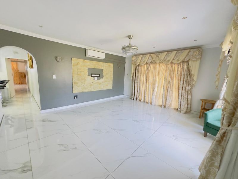 Spacious living room featuring polished marble-look floor tiles, a split-system air conditioner, and a stone feature wall with an integrated media recess.