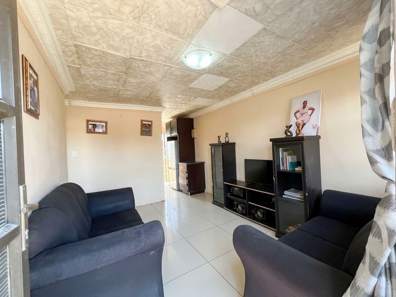 A living room featuring large format floor tiles and a textured ceiling finish, providing a functional space with potential for modern updates.