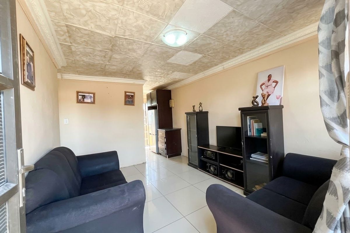 A living room featuring large format floor tiles and a textured ceiling finish, providing a functional space with potential for modern updates.
