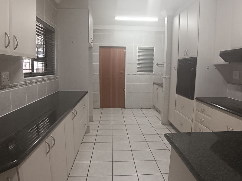 A spacious, functional kitchen featuring granite countertops, ample built-in cabinetry, a built-in oven, and tiled flooring throughout.