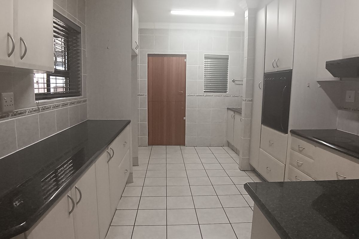 A spacious, functional kitchen featuring granite countertops, ample built-in cabinetry, a built-in oven, and tiled flooring throughout.