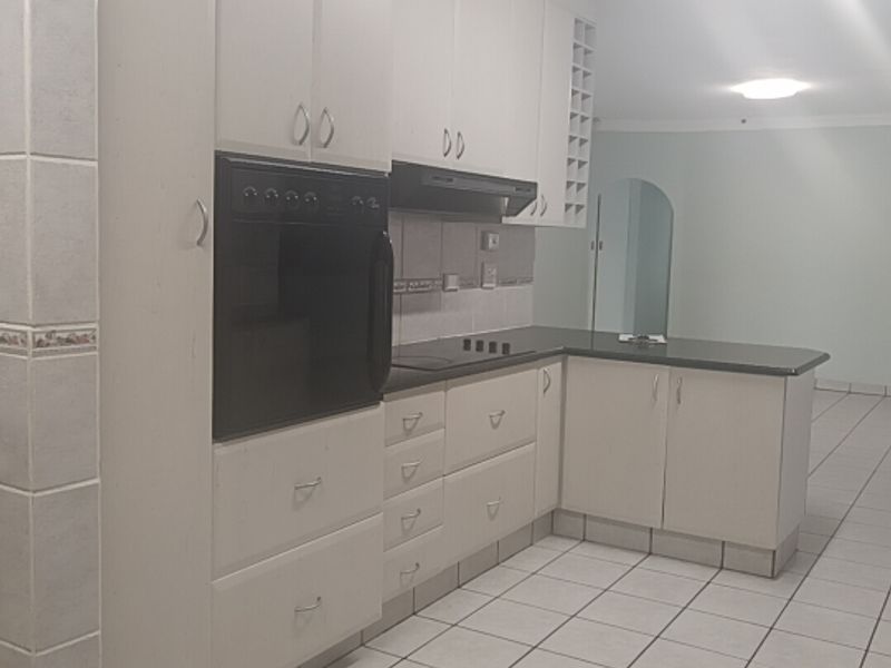 A functional kitchen featuring built-in cabinetry, an integrated oven, hob, extractor fan, and tiled flooring, offering a clean and practical workspace.