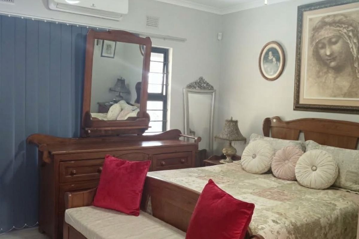A well-maintained bedroom featuring laminate flooring, a ceiling fan, and a wall-mounted air conditioning unit.