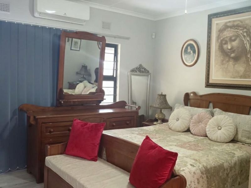 A well-maintained bedroom featuring laminate flooring, a ceiling fan, and a wall-mounted air conditioning unit.