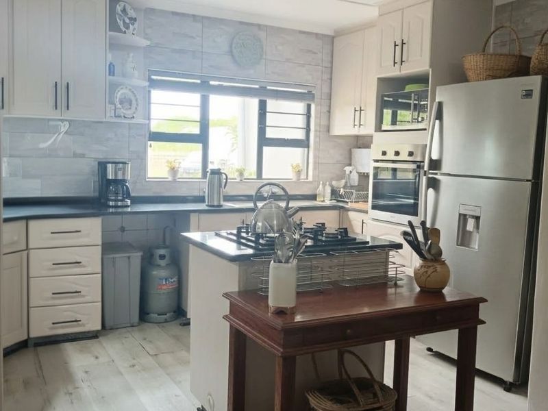 A functional kitchen featuring light-toned cabinetry, a central gas hob, built-in oven, and modern tiled backsplash with ample storage space.