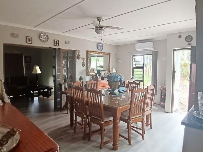 Spacious dining area featuring laminate flooring, a ceiling fan, and a wall-mounted air conditioning unit, with direct access to the outdoor area.