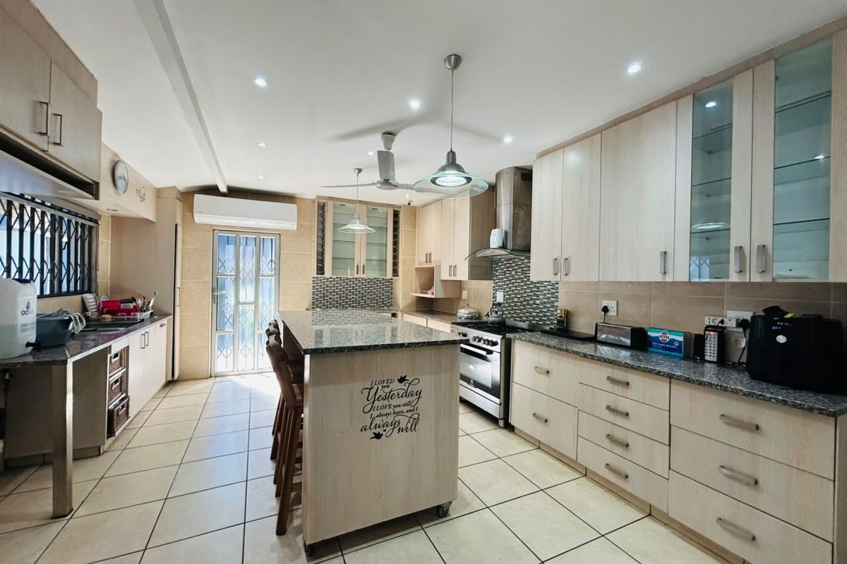 Spacious kitchen featuring light wood cabinetry, granite countertops, a central island, tiled flooring, and modern built-in appliances.