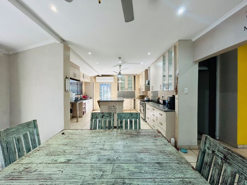 Spacious open-plan kitchen and dining area featuring modern cabinetry, granite countertops, built-in appliances, and recessed lighting.