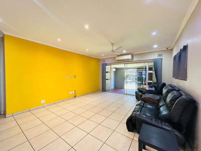 Spacious living room featuring tiled flooring, recessed lighting, a ceiling fan, and split-system air conditioning, with direct access to an outdoor patio area.