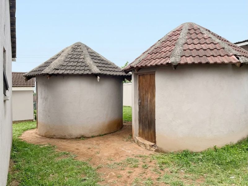 Two circular outbuildings featuring tiled roofs and concrete render walls situated in a rear garden area.