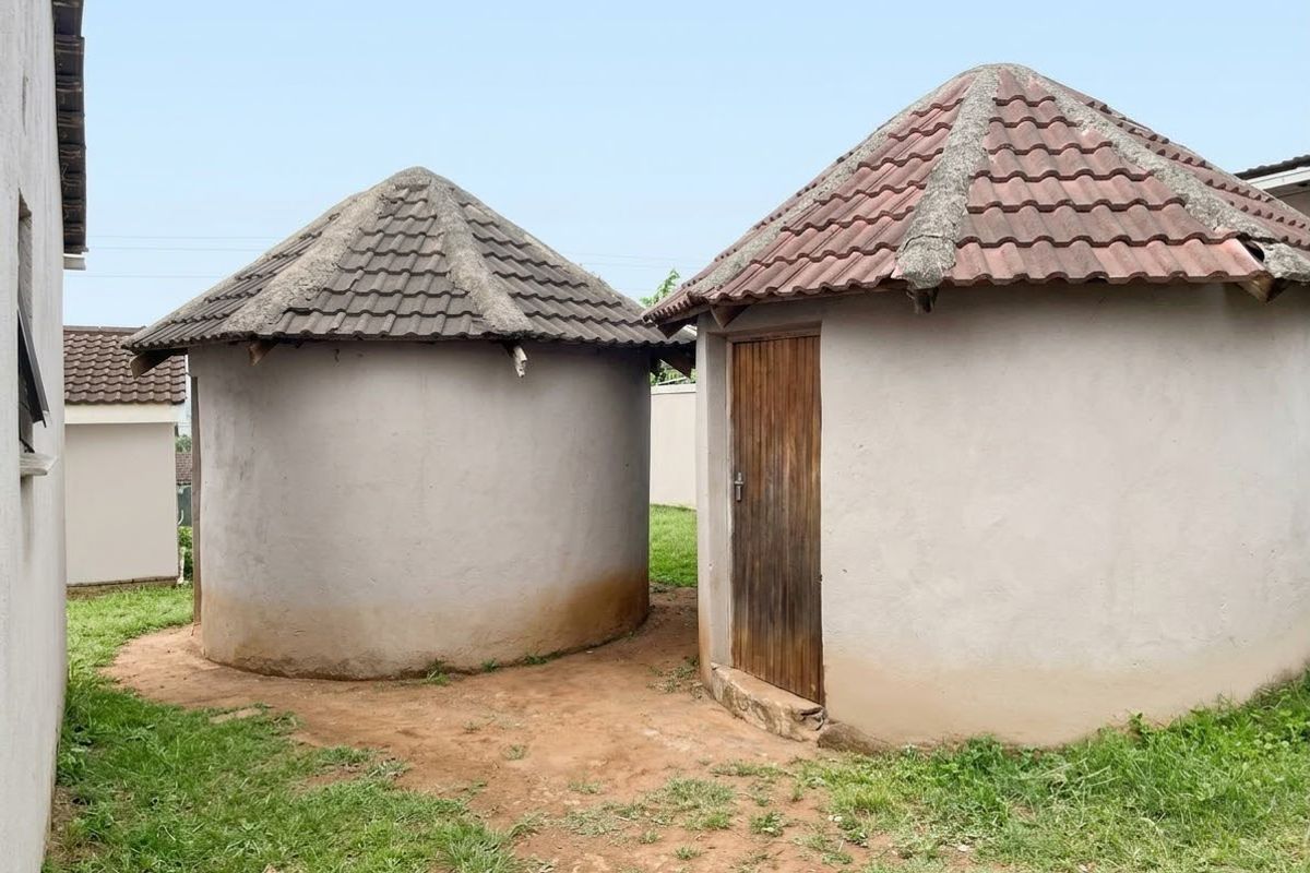 Two circular outbuildings featuring tiled roofs and concrete render walls situated in a rear garden area.