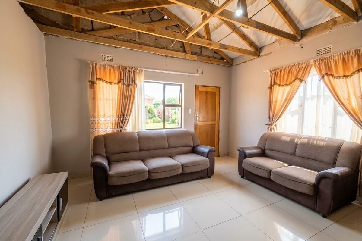 Living room featuring tiled flooring, exposed timber roof trusses, and natural light through aluminium windows.
