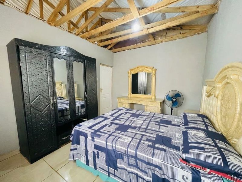 Bedroom featuring tiled flooring and an unfinished ceiling with exposed timber roof trusses, requiring completion to improve the overall finish and aesthetic.