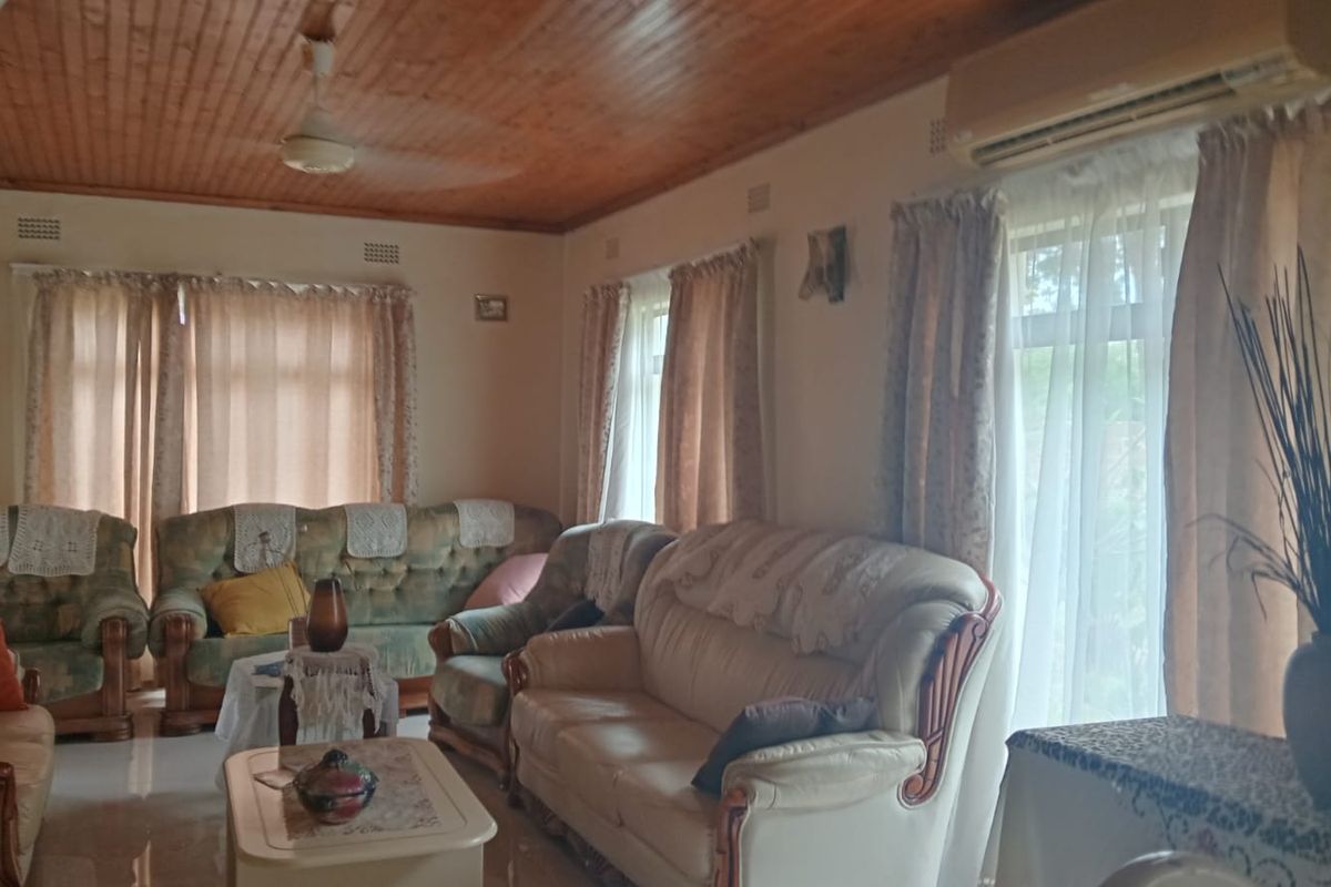 A spacious living room featuring a warm timber tongue and groove ceiling, tiled flooring, and a wall-mounted split system air conditioner.