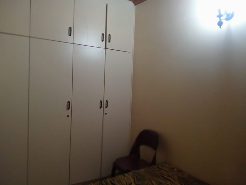 A bedroom featuring floor-to-ceiling built-in cupboards and a wall-mounted light fixture.