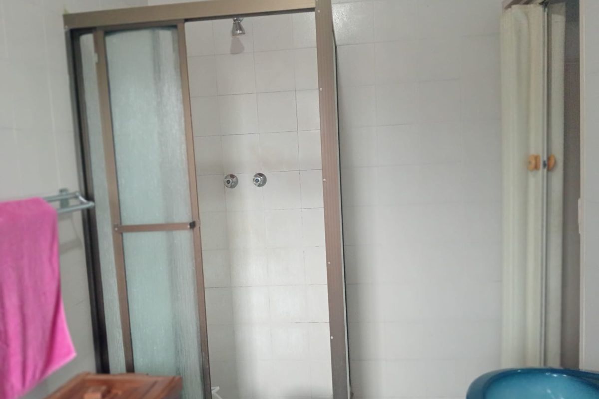 A functional bathroom featuring a shower enclosure with tiled walls, requiring cosmetic updates to modernize the space.