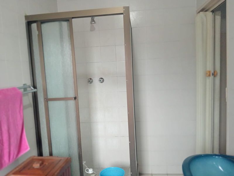 A functional bathroom featuring a shower enclosure with tiled walls, requiring cosmetic updates to modernize the space.