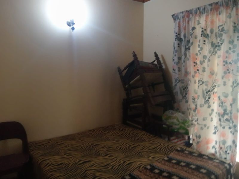A bedroom featuring a wall-mounted light fixture and window with curtains.