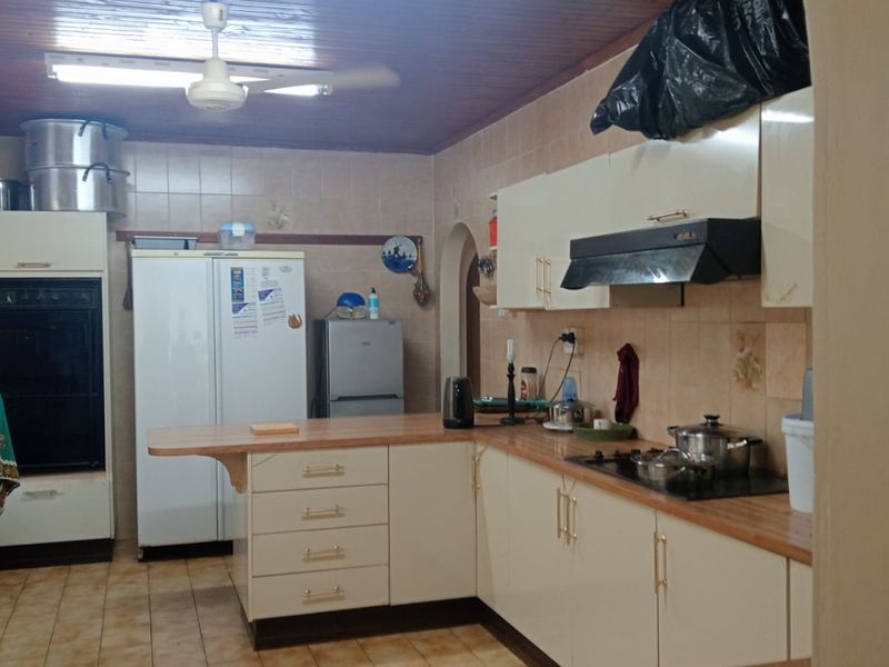 A functional kitchen featuring built-in cabinetry, laminate countertops, a built-in oven, and a timber ceiling, offering potential for modernization.