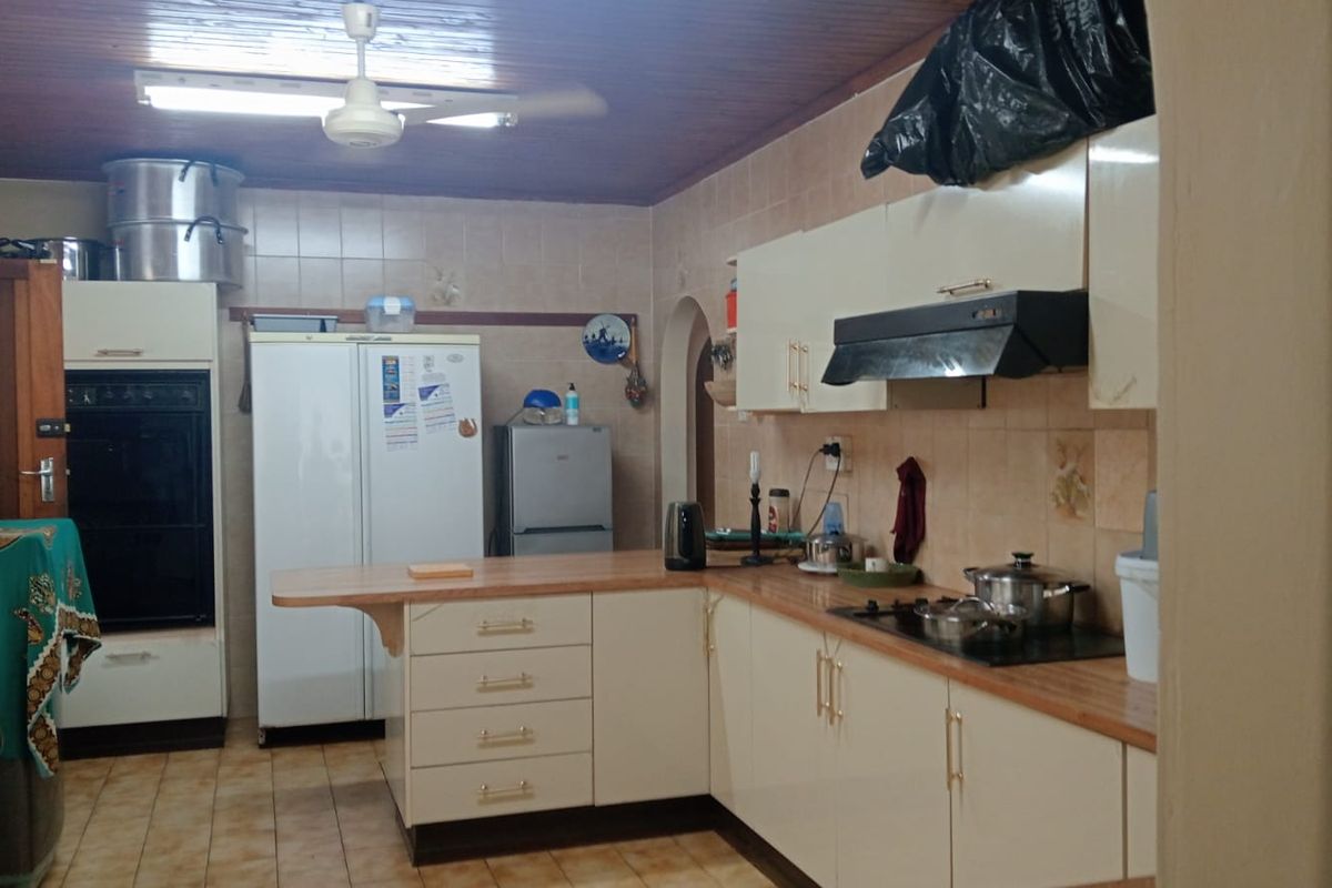 A functional kitchen featuring built-in cabinetry, laminate countertops, a built-in oven, and a timber ceiling, offering potential for modernization.