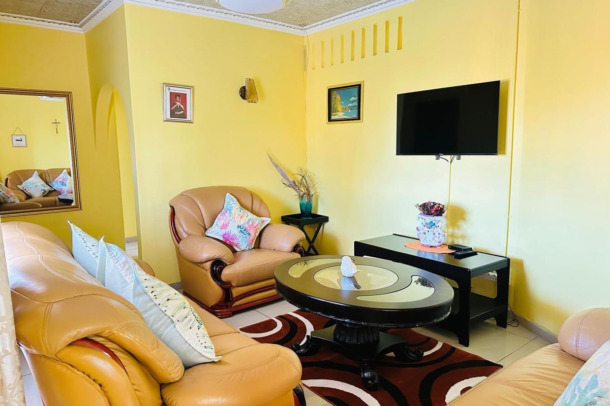 A living room featuring yellow walls, tiled flooring, and a textured ceiling, providing a functional and bright space for relaxation.