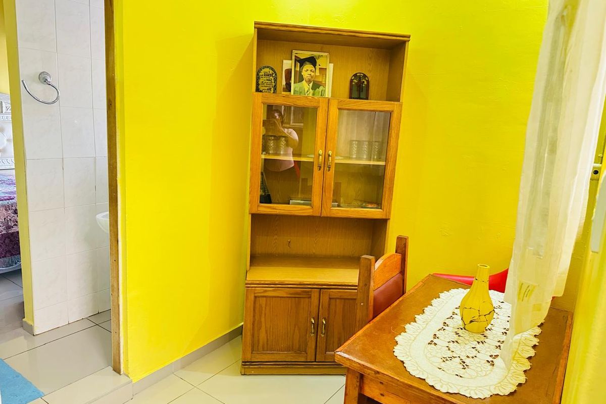 A view of a room with bright yellow walls and tiled flooring, featuring an adjacent bathroom entrance.