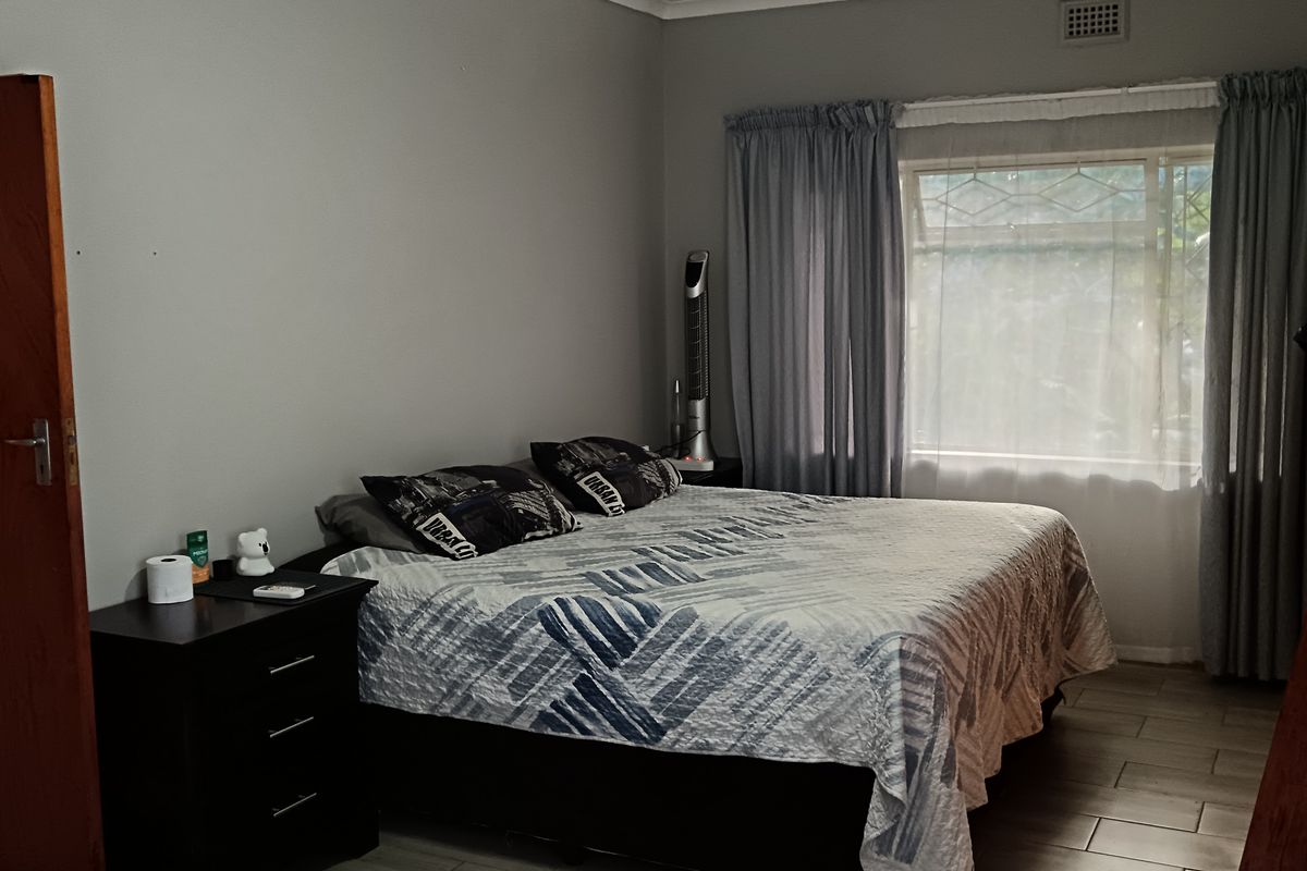 A bedroom featuring tiled flooring, a ceiling fan, and a window with curtains.