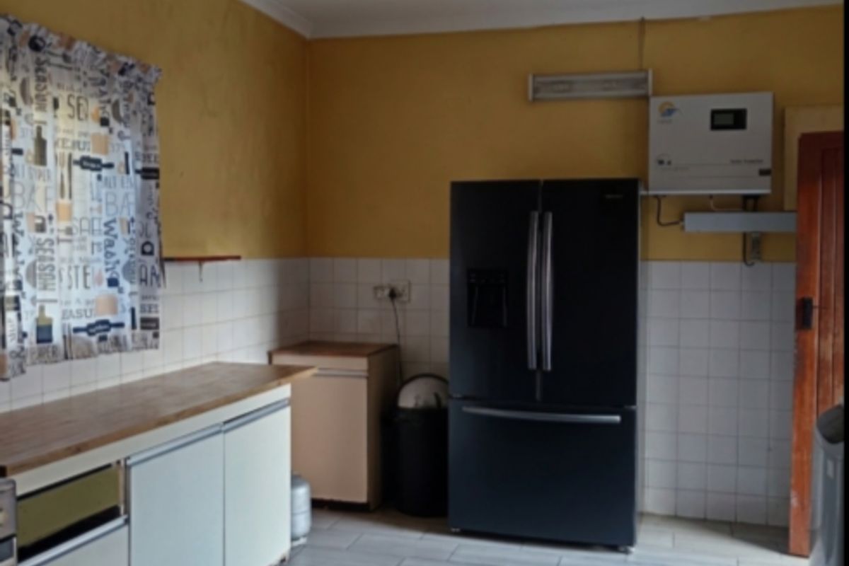 A functional kitchen area featuring tiled flooring, built-in cabinetry, a ceiling fan, and a wall-mounted inverter system.
