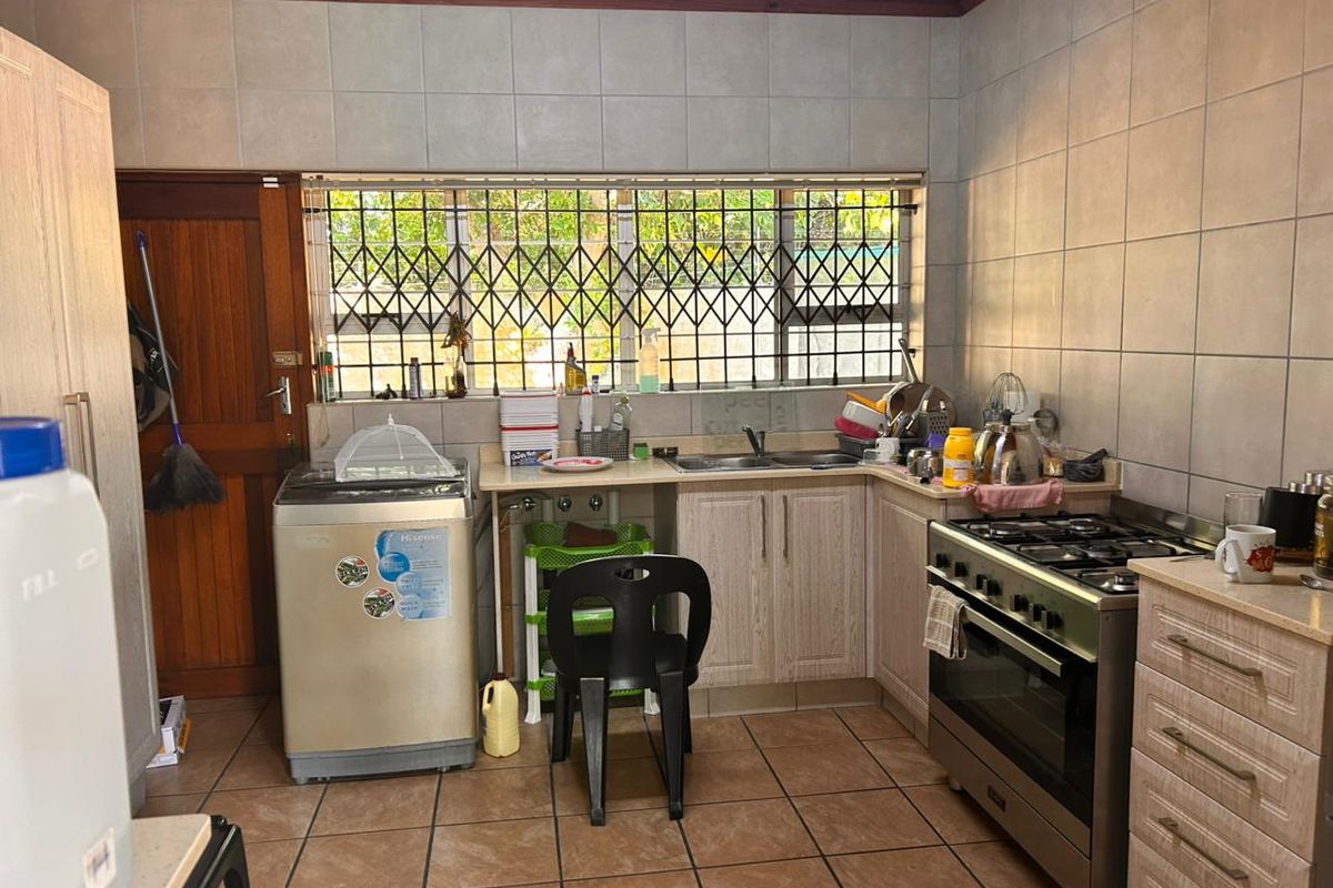 Functional kitchen featuring tiled walls, built-in cabinetry, a stainless steel gas stove, and a double sink with security bars on the window.
