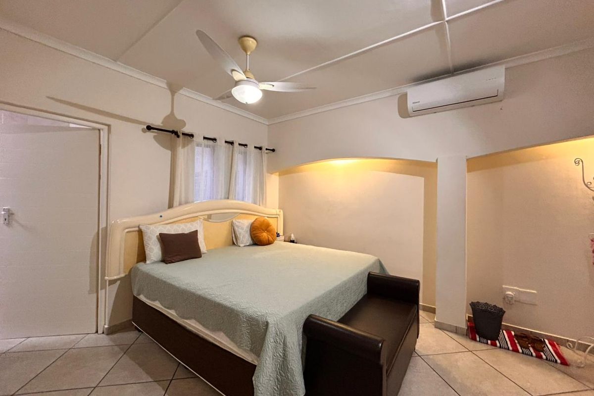 A bedroom featuring tiled flooring, a ceiling fan, and a wall-mounted air conditioning unit.