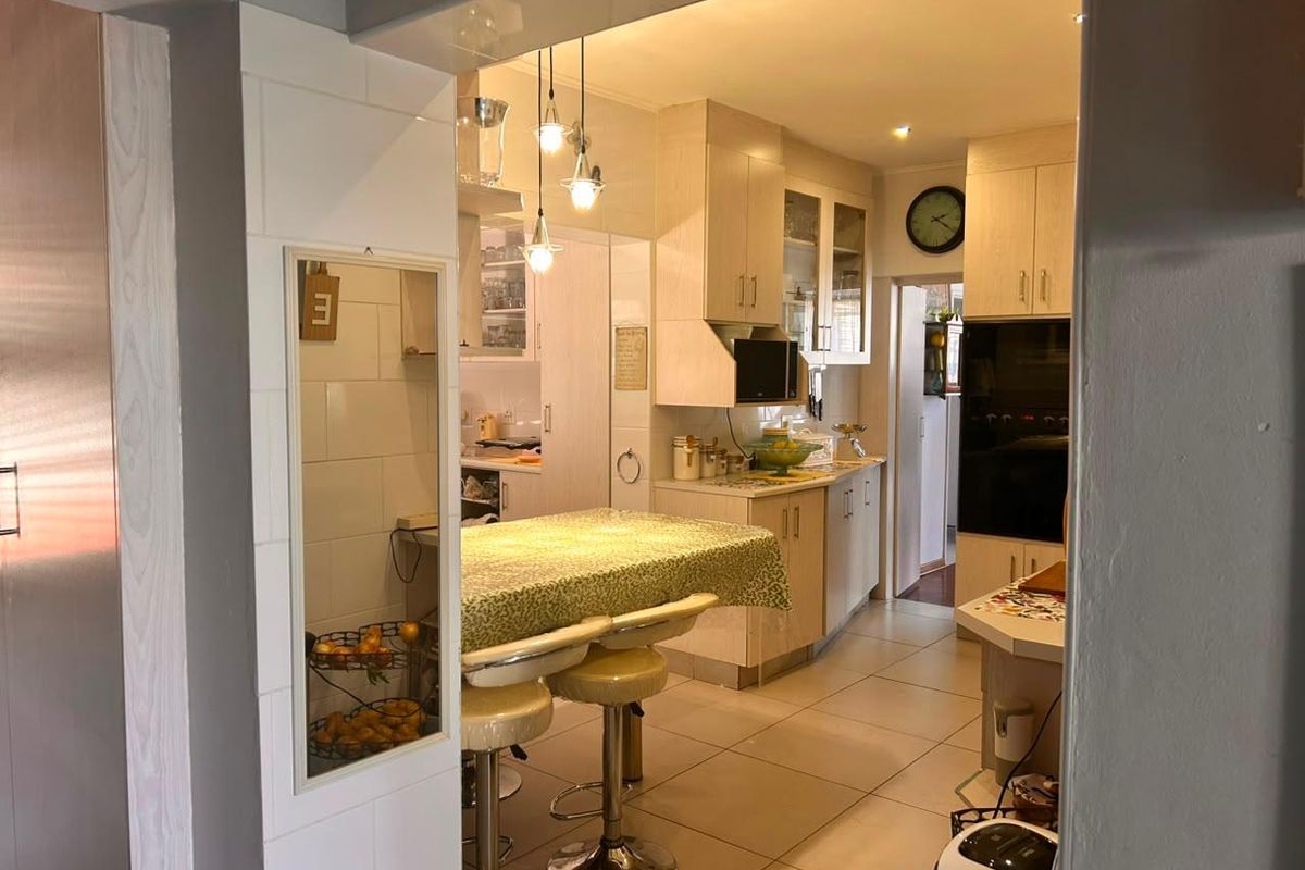 A functional kitchen featuring light-toned built-in cabinetry, tiled flooring, and integrated oven, offering a practical layout with ample storage and preparation space.