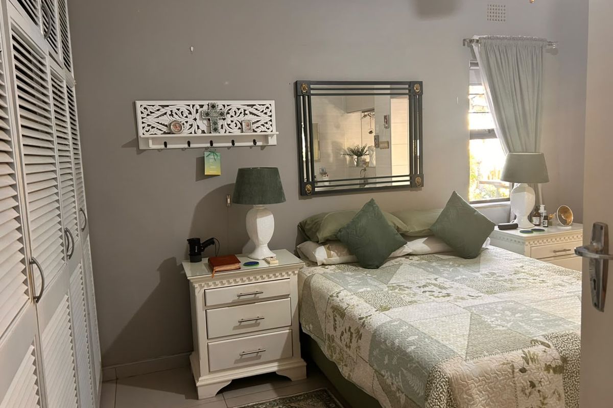 A comfortable bedroom featuring built-in cupboards, tiled flooring, and neutral wall tones, offering a functional and well-maintained living space.