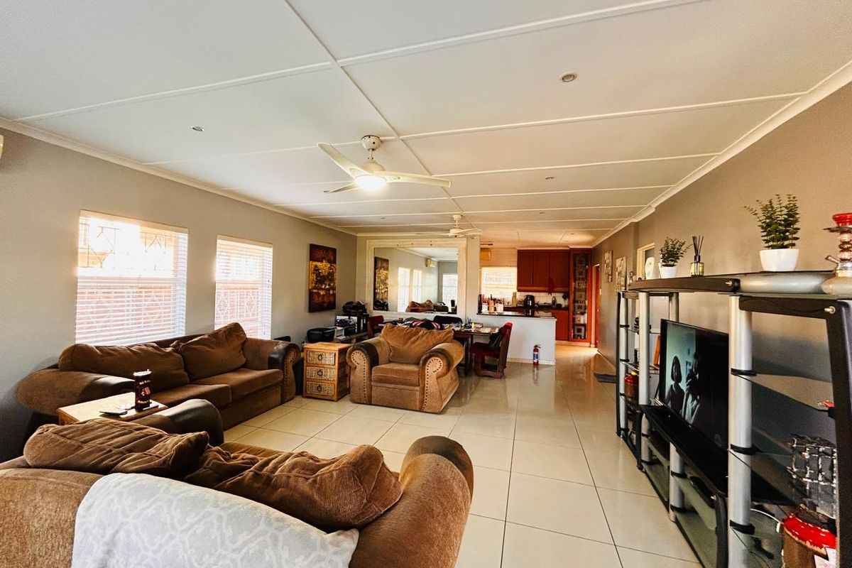 Spacious open-plan living and dining area featuring tiled flooring, ceiling fans, and a functional kitchen with a breakfast counter.