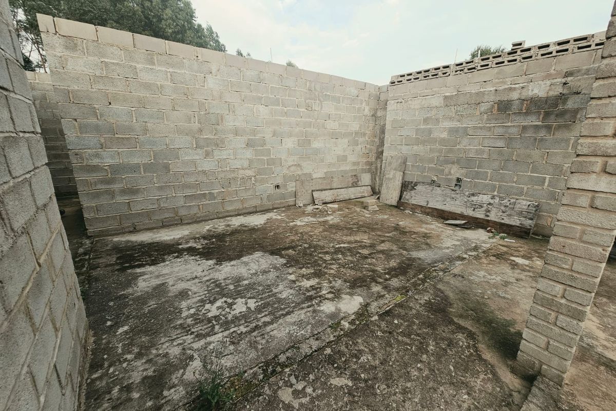 An unfinished construction area featuring exposed concrete block walls and a weathered concrete slab floor, suitable for further development or renovation.