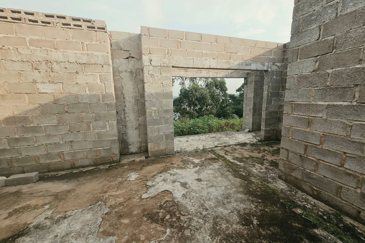 An unfinished construction space featuring exposed concrete block walls and a concrete slab floor, offering a blank canvas for development.
