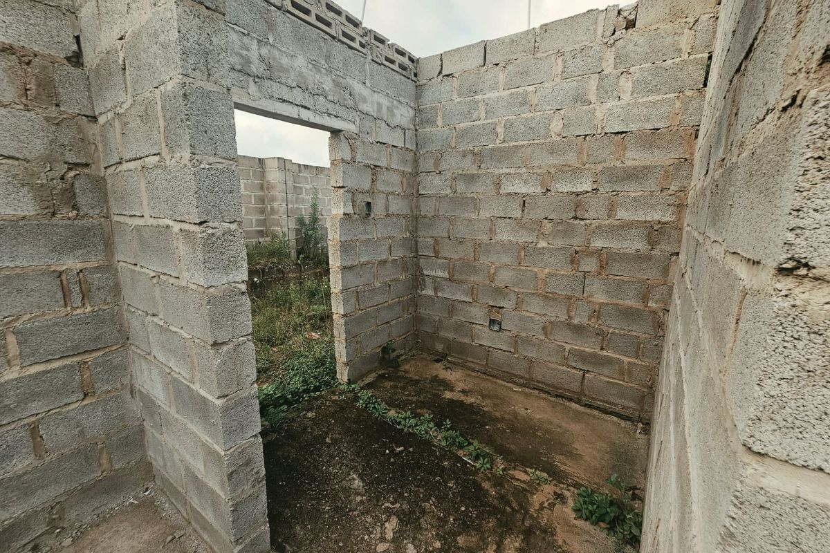 An unfinished construction site showing exposed concrete block walls and an open-plan layout, requiring significant completion and finishing work.