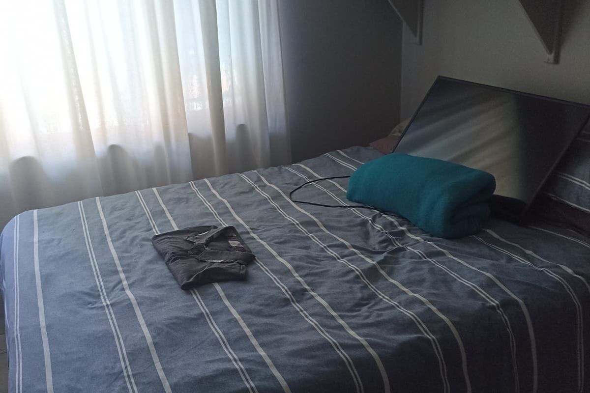 A bedroom featuring tiled flooring and a wall-mounted shelf.