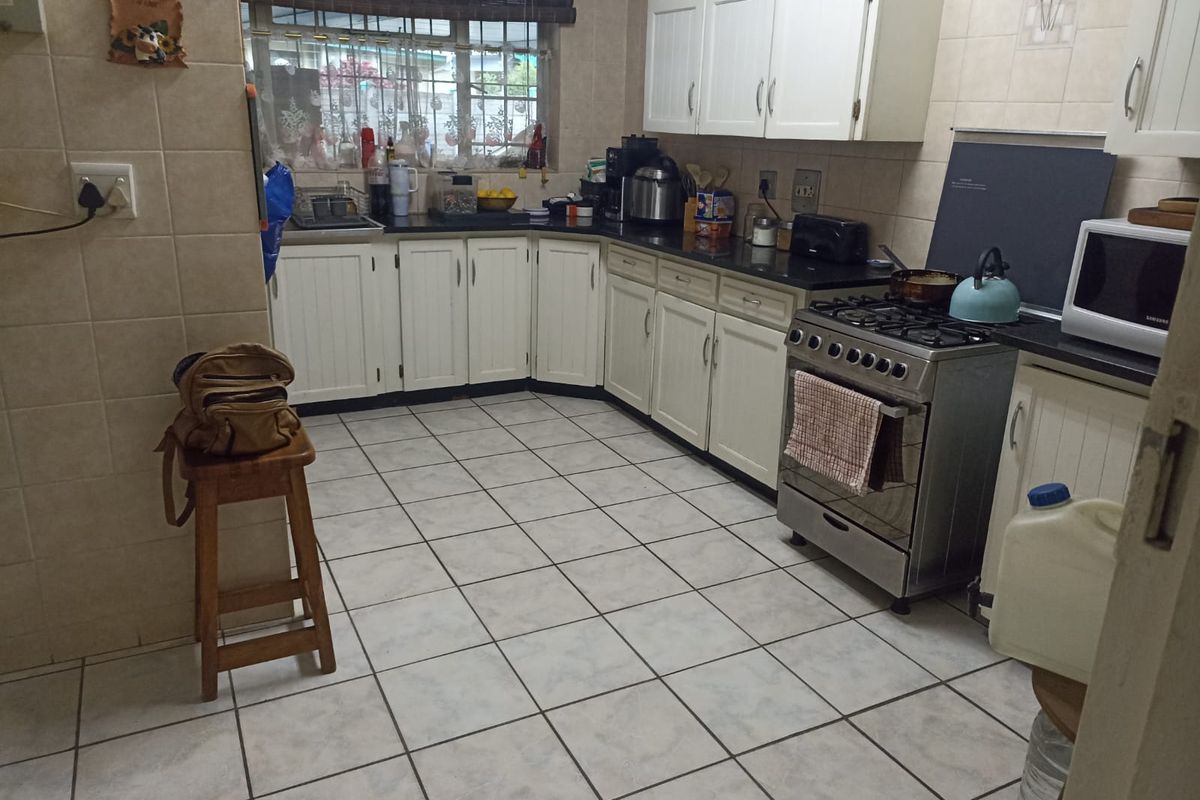 A functional kitchen featuring white cabinetry, tiled flooring, and a freestanding gas stove with an integrated oven.