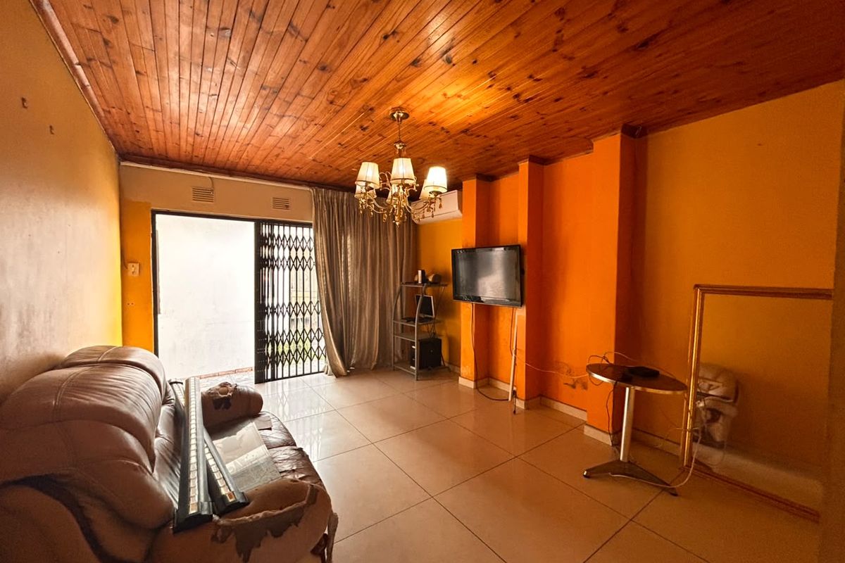 Living room featuring a timber ceiling, tiled flooring, and a sliding door with a security gate, providing access to the exterior.