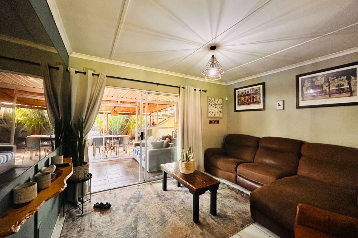 A comfortable living room featuring tiled flooring, a coved ceiling, and a large sliding glass door providing direct access to the outdoor patio area.