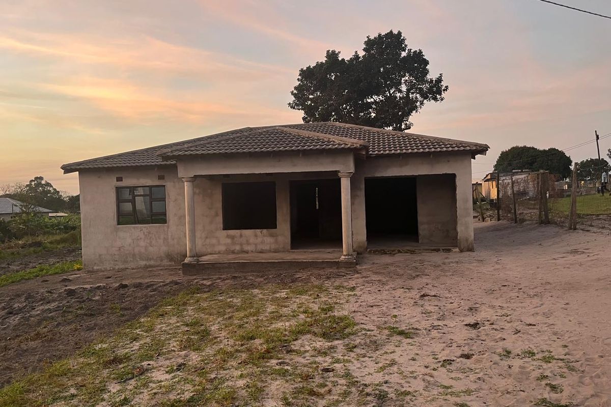 A single-story house under construction featuring a tiled roof, covered porch with concrete columns, and unfinished exterior masonry walls.